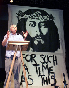 Paul Grout preaching in front of the banner he painted at National Youth Conference 2002